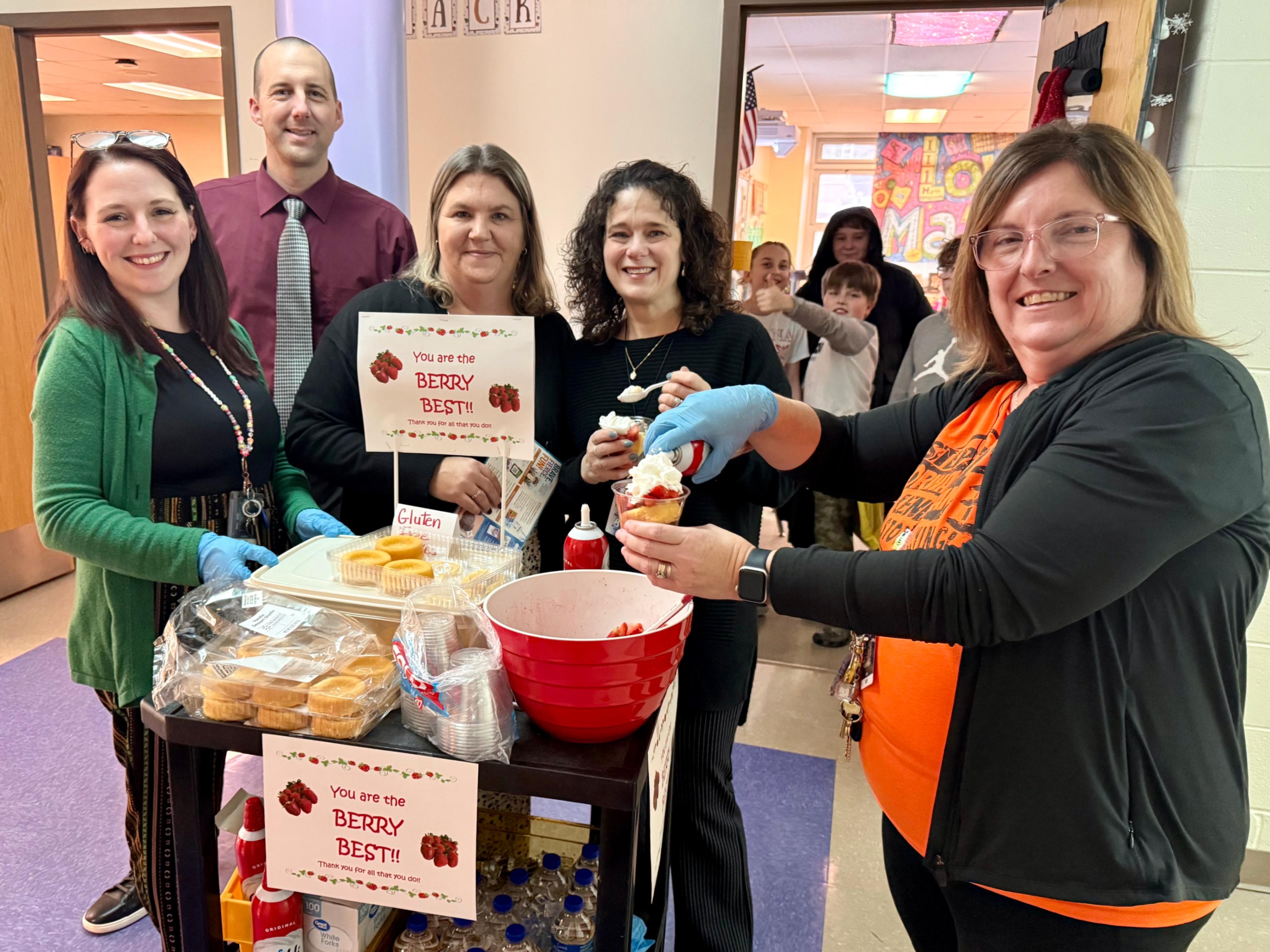 Staff members with the Sunshine Cart prepare strawberry shortcake for teachers.